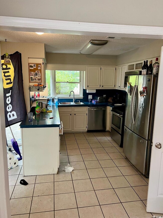 Kitchen featuring white cabinets, light tile patte