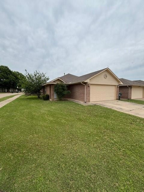 View of front of property with brick siding, a garage, driveway, and a front yard