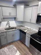 Kitchen with appliances with stainless steel finishes, a sink, light wood finished floors, and gray cabinets