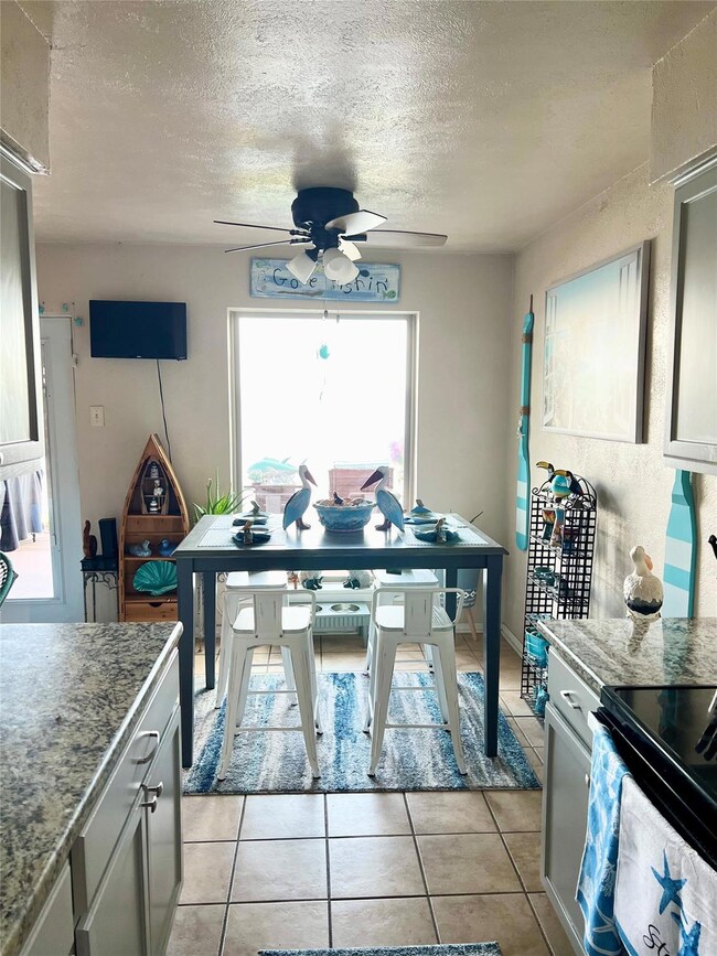Tiled dining area featuring a textured ceiling and ceiling fan