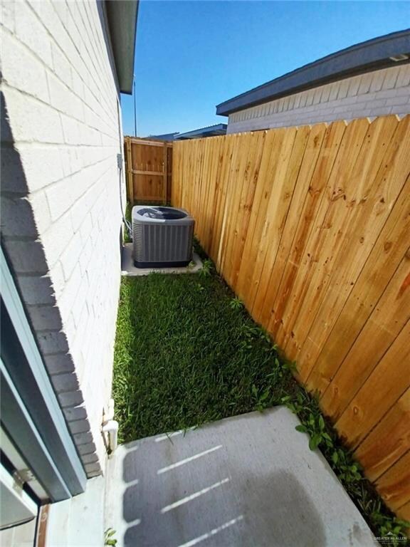 View of yard with central AC and fence