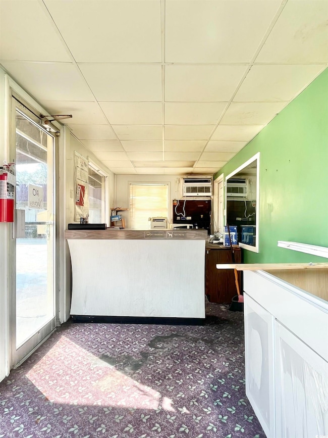 Kitchen with carpet, a drop ceiling, and a wall unit AC