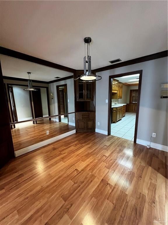 Unfurnished living room featuring ornamental molding, light wood-style flooring, and a ceiling fan