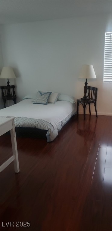 Bedroom with dark wood finished floors and baseboards