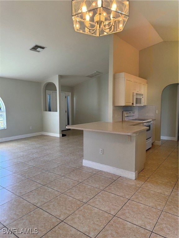 Kitchen featuring range, light tile patterned floors, kitchen peninsula, and a breakfast bar area