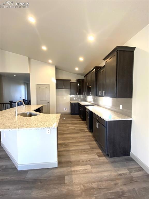 Kitchen with wood-type flooring, an island with si