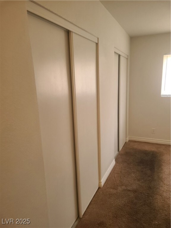 Hallway with carpet floors and baseboards