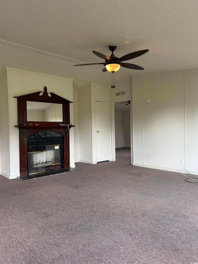 Unfurnished living room with ceiling fan, a textur