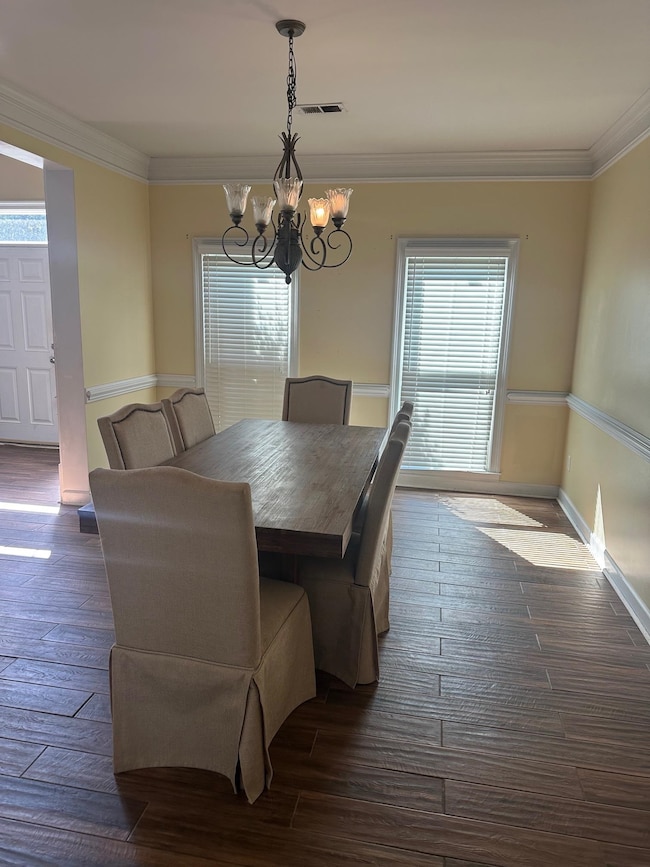 Dining room featuring crown molding, dark wood-style flooring, and a chandelier