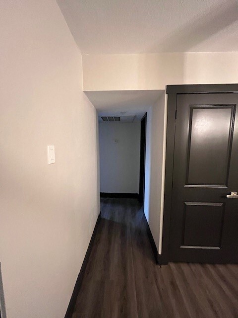 Hall featuring dark wood finished floors and baseboards