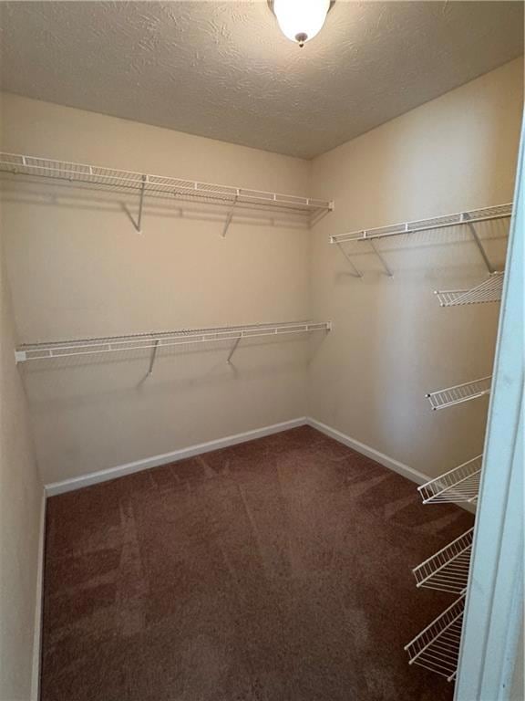 Walk in closet featuring dark carpet