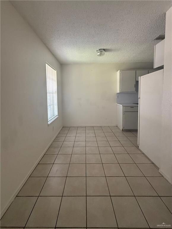 Empty room with a textured ceiling and light tile patterned flooring