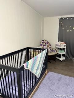 Bedroom featuring dark wood-style floors and a nursery area