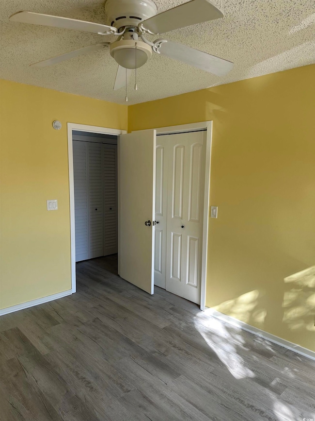 Unfurnished bedroom featuring wood finished floors, a textured ceiling, and a ceiling fan