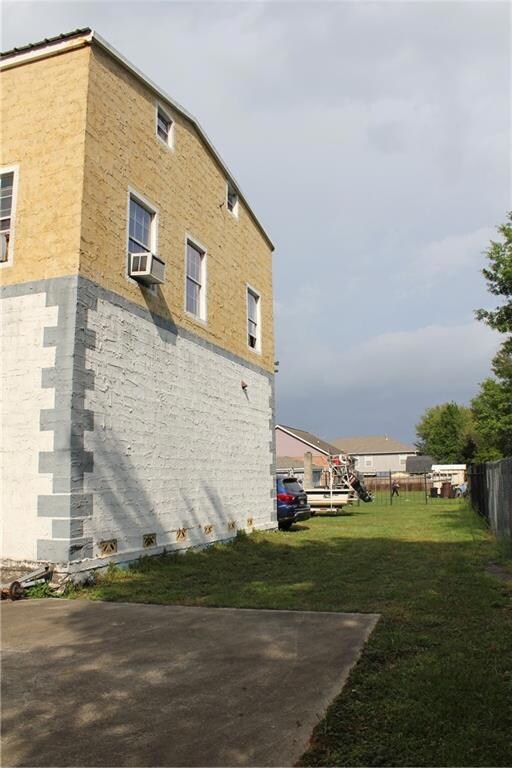 Rear view of home looking east toward adjacent vacant lot. Fence behind the residence is chain-link. Fence behind the vacant lot is decorative iron.