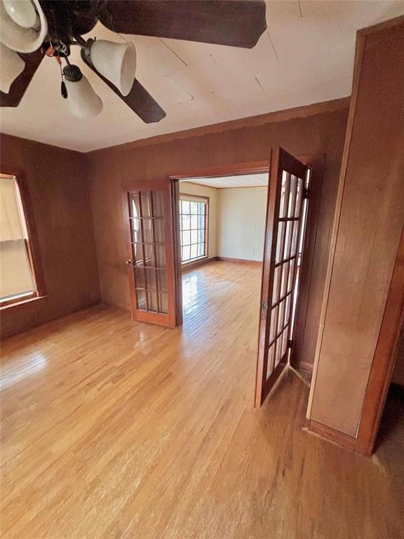 Empty room featuring wood walls, light wood-style flooring, and ceiling fan