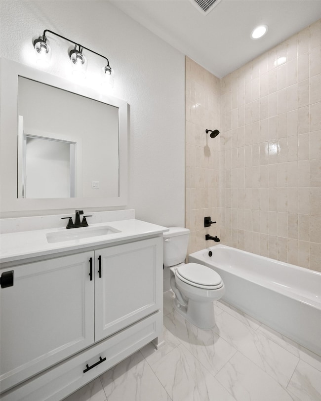 Full bathroom featuring vanity, washtub / shower combination, recessed lighting, and light marble finish flooring