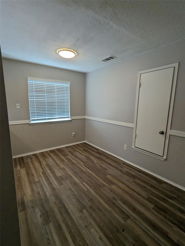 Empty room featuring dark wood-style floors, a te