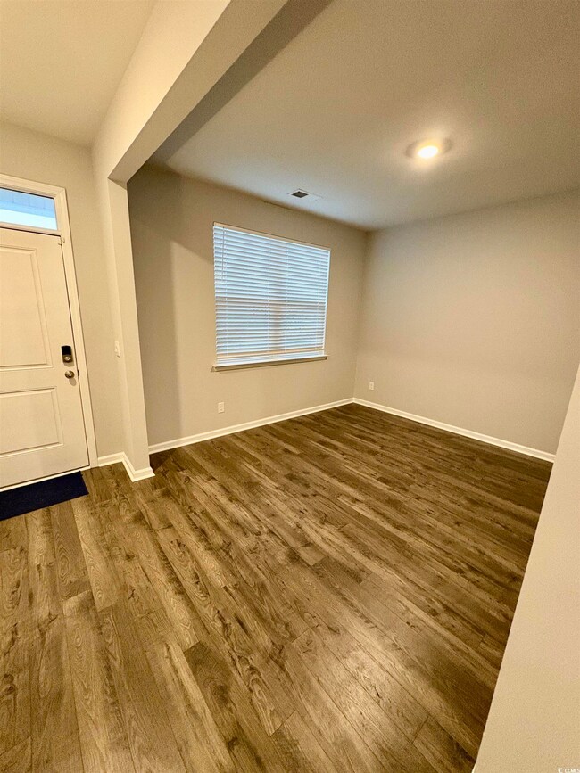 Foyer with dark wood-style flooring and baseboards