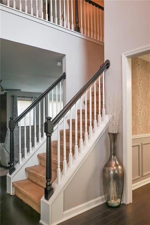 Stairway with wood finished floors and a wainscoted wall