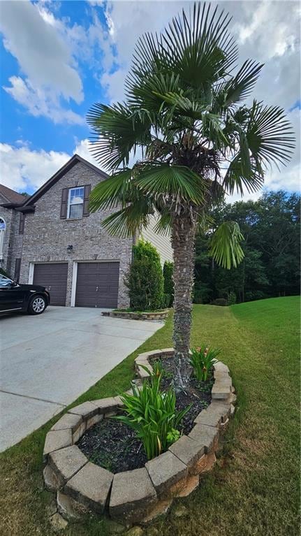 View of side of property with an attached garage, driveway, a lawn, and stone siding