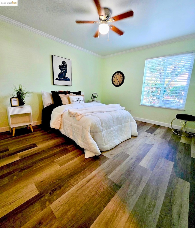 Bedroom featuring ornamental molding, ceiling fan, and wood finished floors