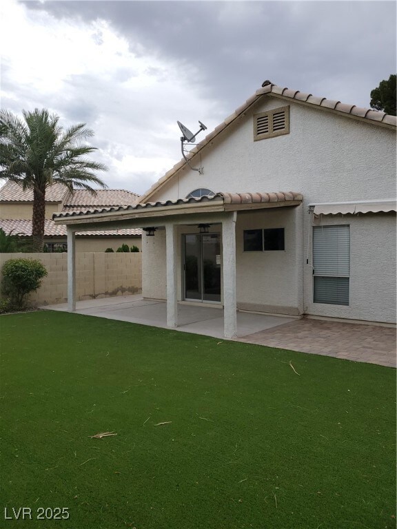 Back of house featuring a patio area, a tiled roof