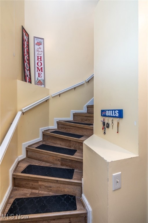 Staircase with wood finished floors and baseboards
