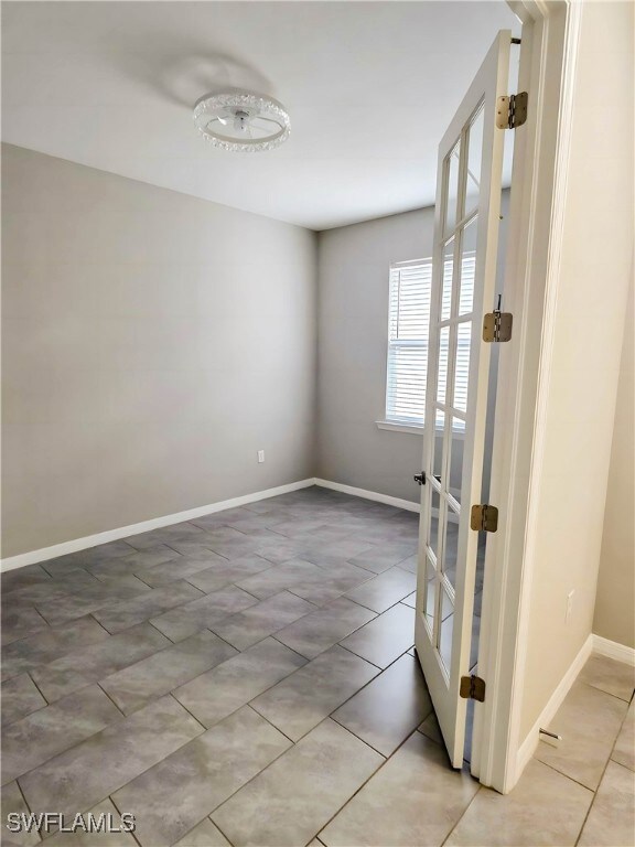 Unfurnished room featuring baseboards and light ti