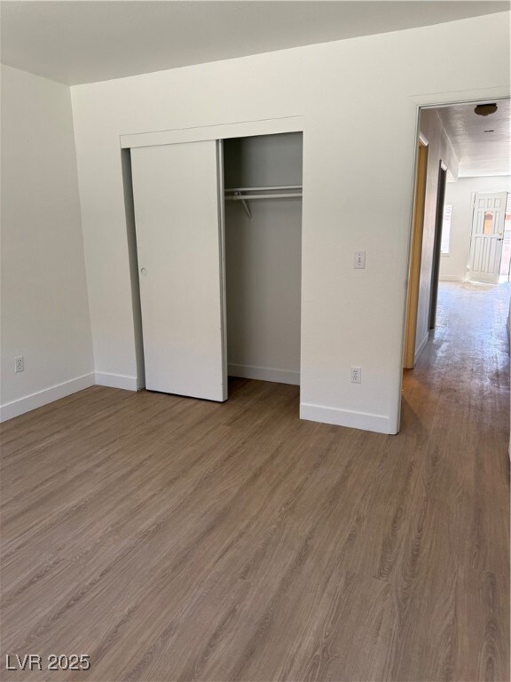 Bedroom with wood finished floors and a closet