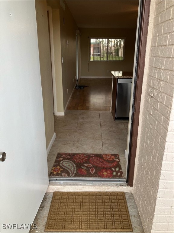 Hall featuring tile patterned floors, brick wall,