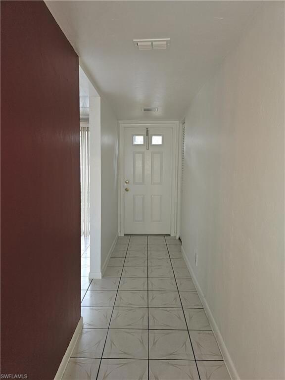 Corridor with baseboards and light tile patterned floors