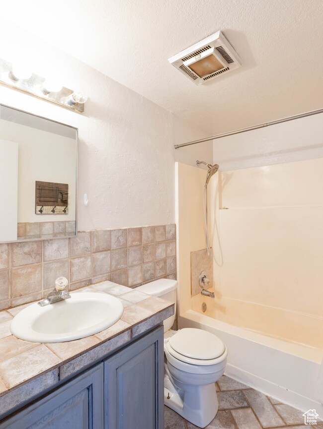 Full bathroom with vanity,  shower combination, toilet, and tasteful backsplash