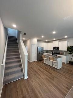 Kitchen featuring freestanding refrigerator, white cabinetry, dark wood-type flooring, baseboards, and recessed lighting