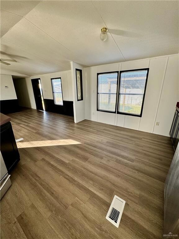 Unfurnished room featuring plenty of natural light, dark wood-type flooring, and ceiling fan