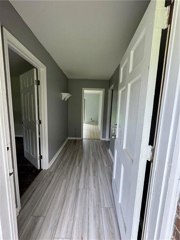 Corridor with light wood-style flooring and baseboards