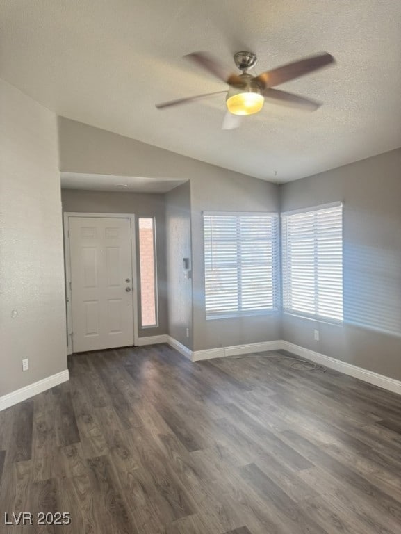 Entrance foyer with dark wood-style flooring, lofted ceiling, a ceiling fan, and a textured ceiling