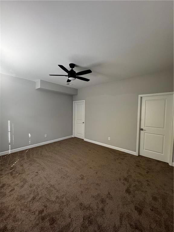 Unfurnished bedroom featuring dark carpet and a ceiling fan