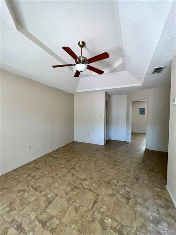 Living room featuring a textured ceiling, a tray ceiling, visible vents, and ceiling fan