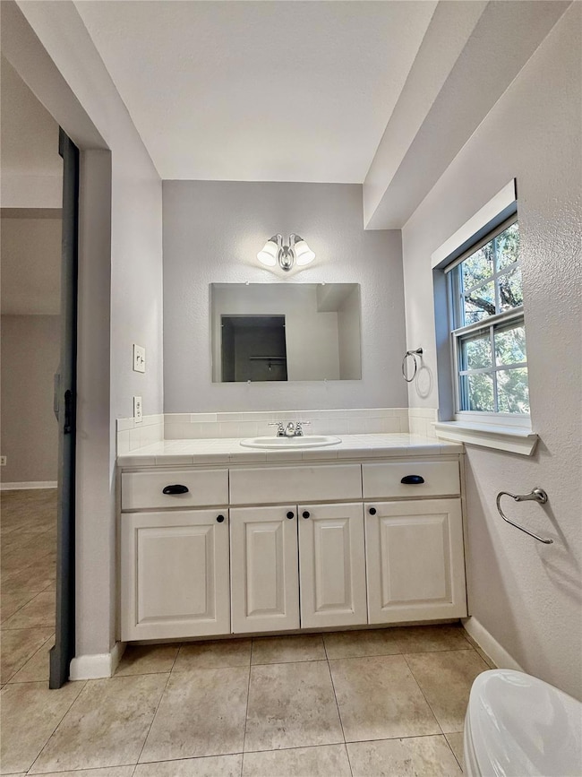 Half bathroom with vanity, light tile patterned floors, and a textured wall