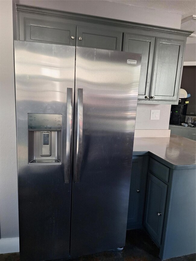Kitchen featuring gray cabinetry and stainless steel refrigerator with ice dispenser