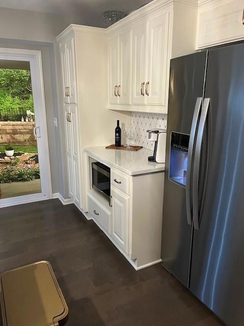 Kitchen featuring fridge, backsplash, white cabinetry, and dark hardwood / wood-style floors