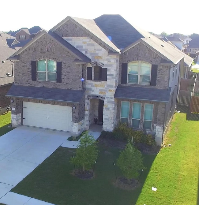 View of front of property featuring concrete driveway, a garage, brick siding, and stone siding