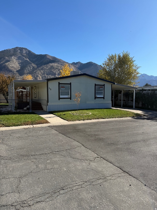 View of front of home featuring a mountain view, an attached carport, and a front lawn