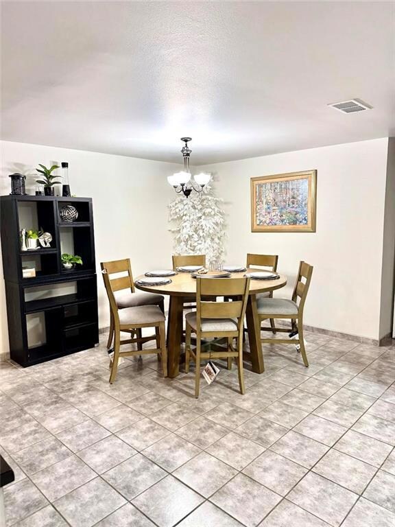 Dining space with a notable chandelier, visible vents, a textured ceiling, and light tile patterned flooring
