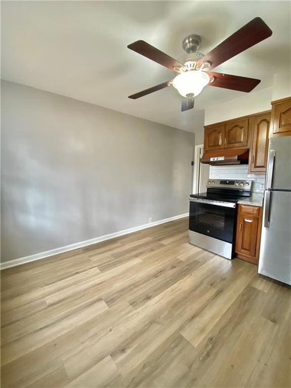 Kitchen with brown cabinets, appliances with stainless steel finishes, tasteful backsplash, ceiling fan, and light wood finished floors