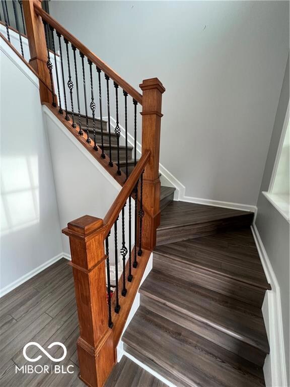 staircase featuring baseboards and wood finished floors