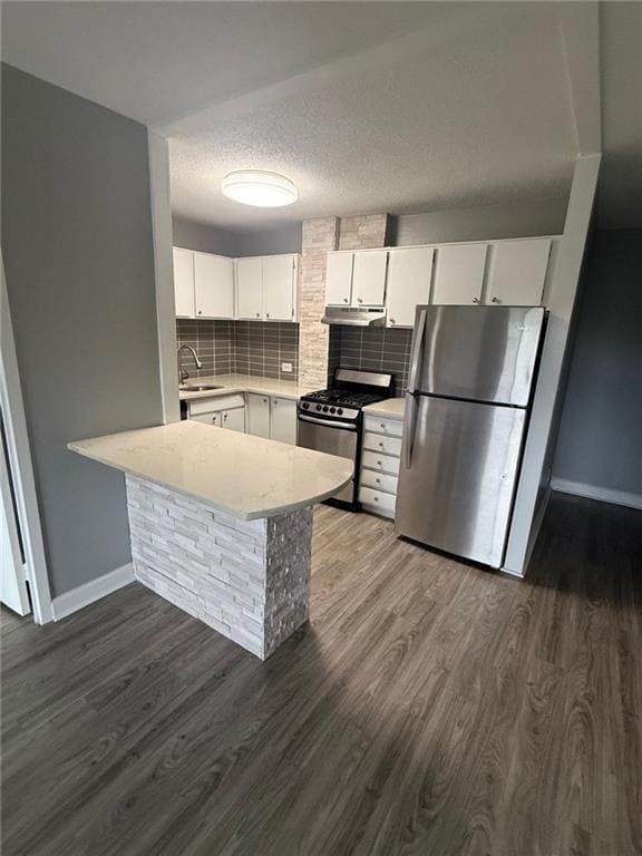 Kitchen with backsplash, white cabinets, a peninsula, stainless steel appliances, and dark wood-type flooring