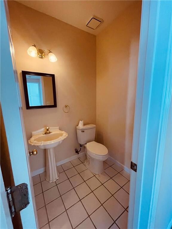Half bathroom with toilet, tile patterned flooring