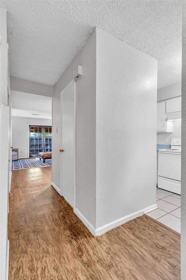 Hallway with a textured ceiling and light hardwood